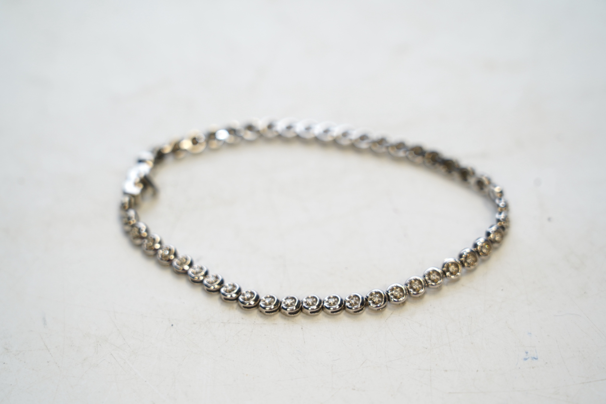 A modern 9ct white gold and diamond chip set line bracelet, 19.5cm, gross weight 8.9 grams. Condition - fair